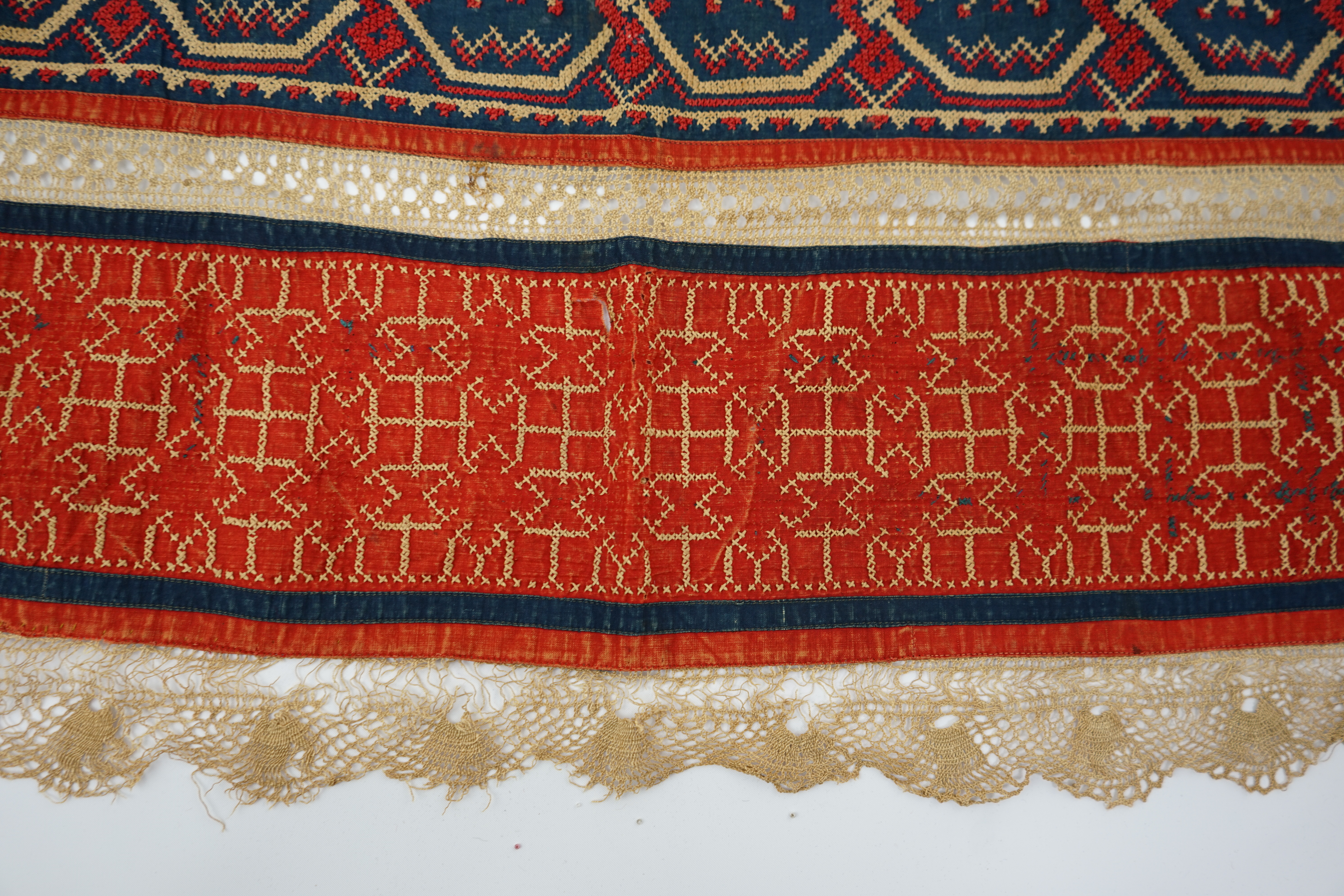 An Eastern European, possibly Ukrainian, apron and a Norwegian beaded bodice front, with child’s cap, the apron worked in rows of coloured cotton, embroidered with cross stitch patterns and lace insertions, the bodice, b